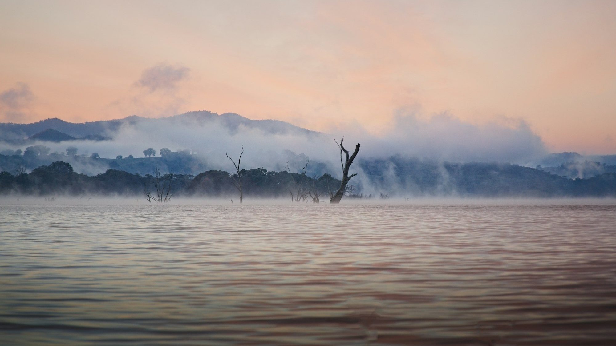Mist lifting off Lake Eildon at dawn, with ranges beyond
