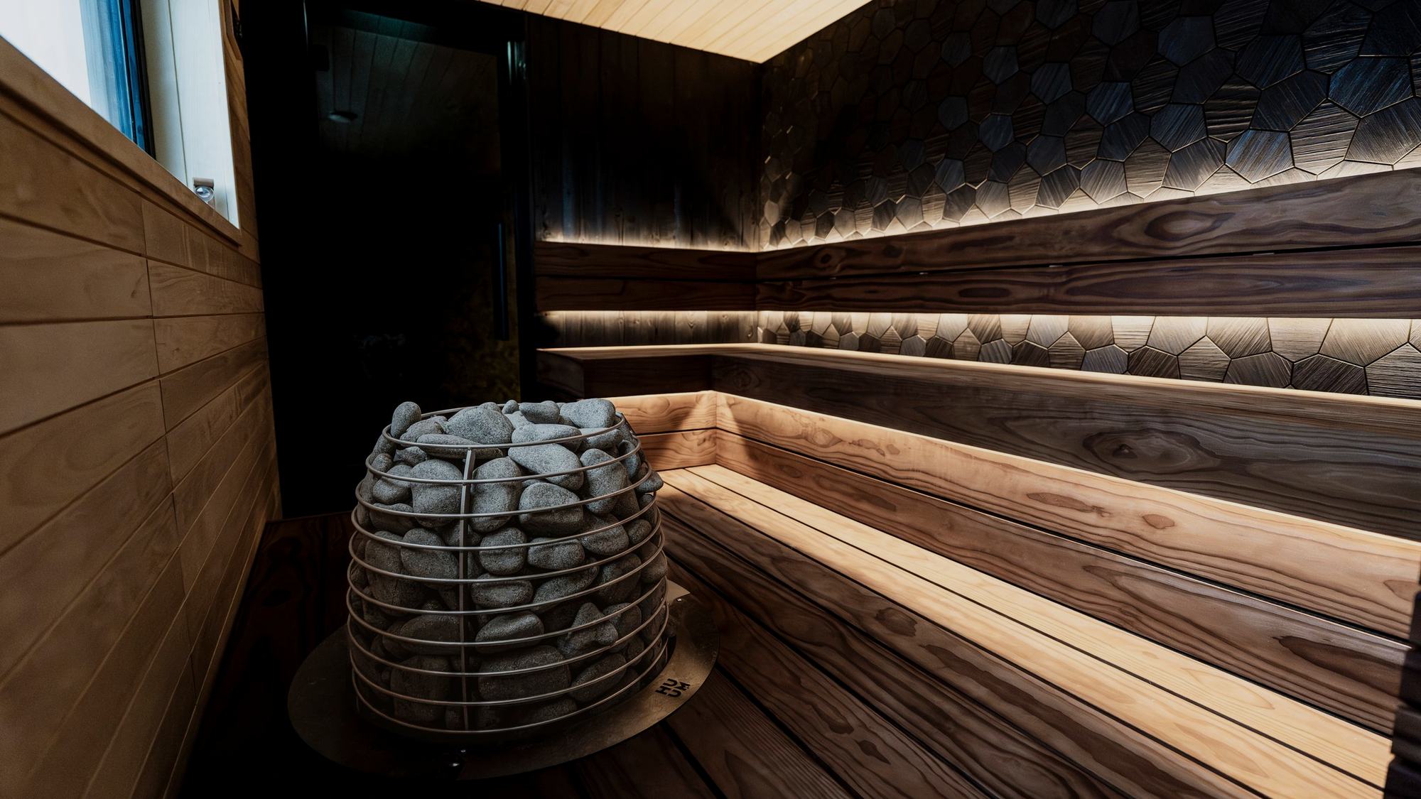 A timber sauna with a stone heater, lit low