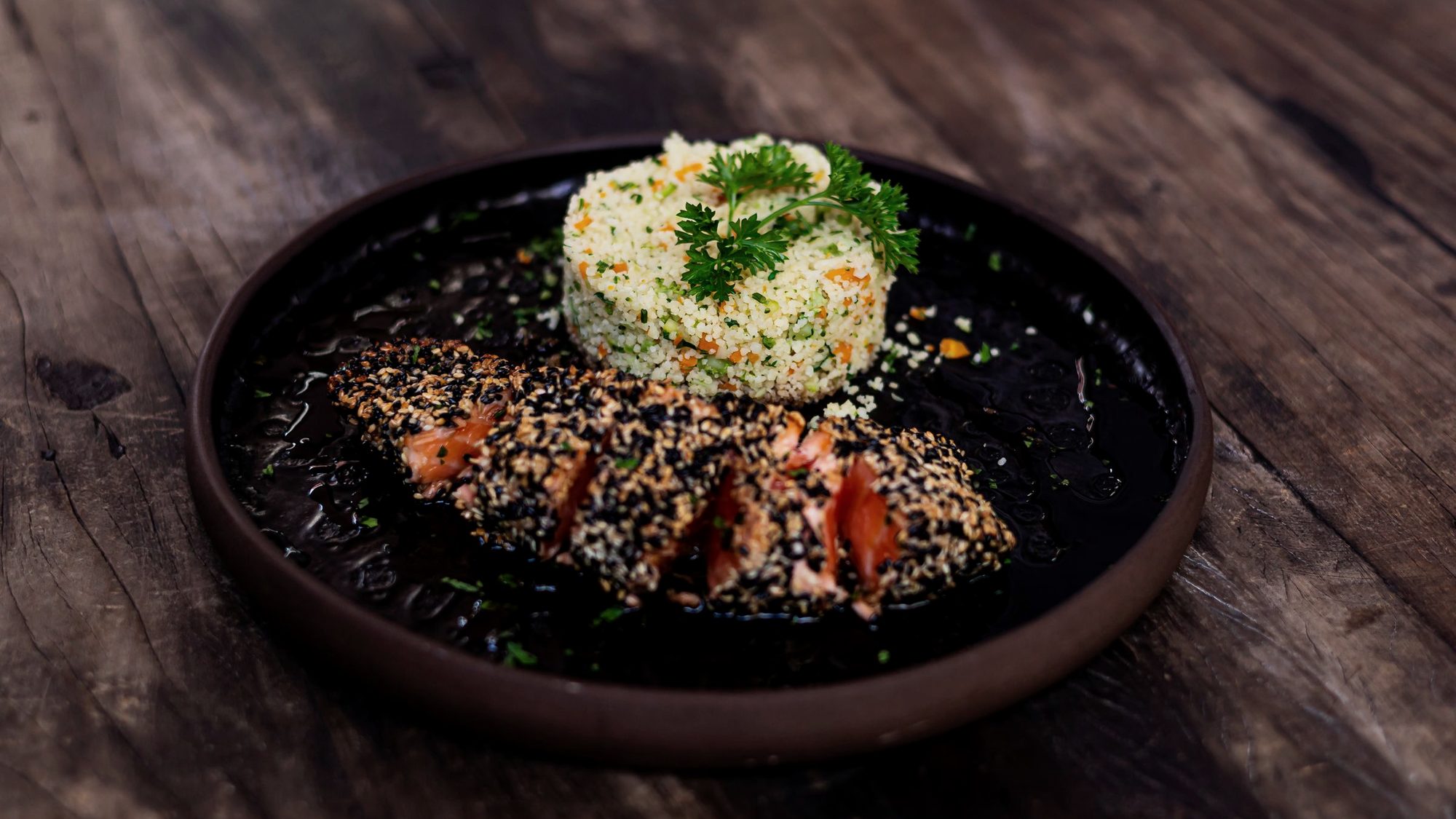 A seasonal plate of fish, grains and herbs on a dark table