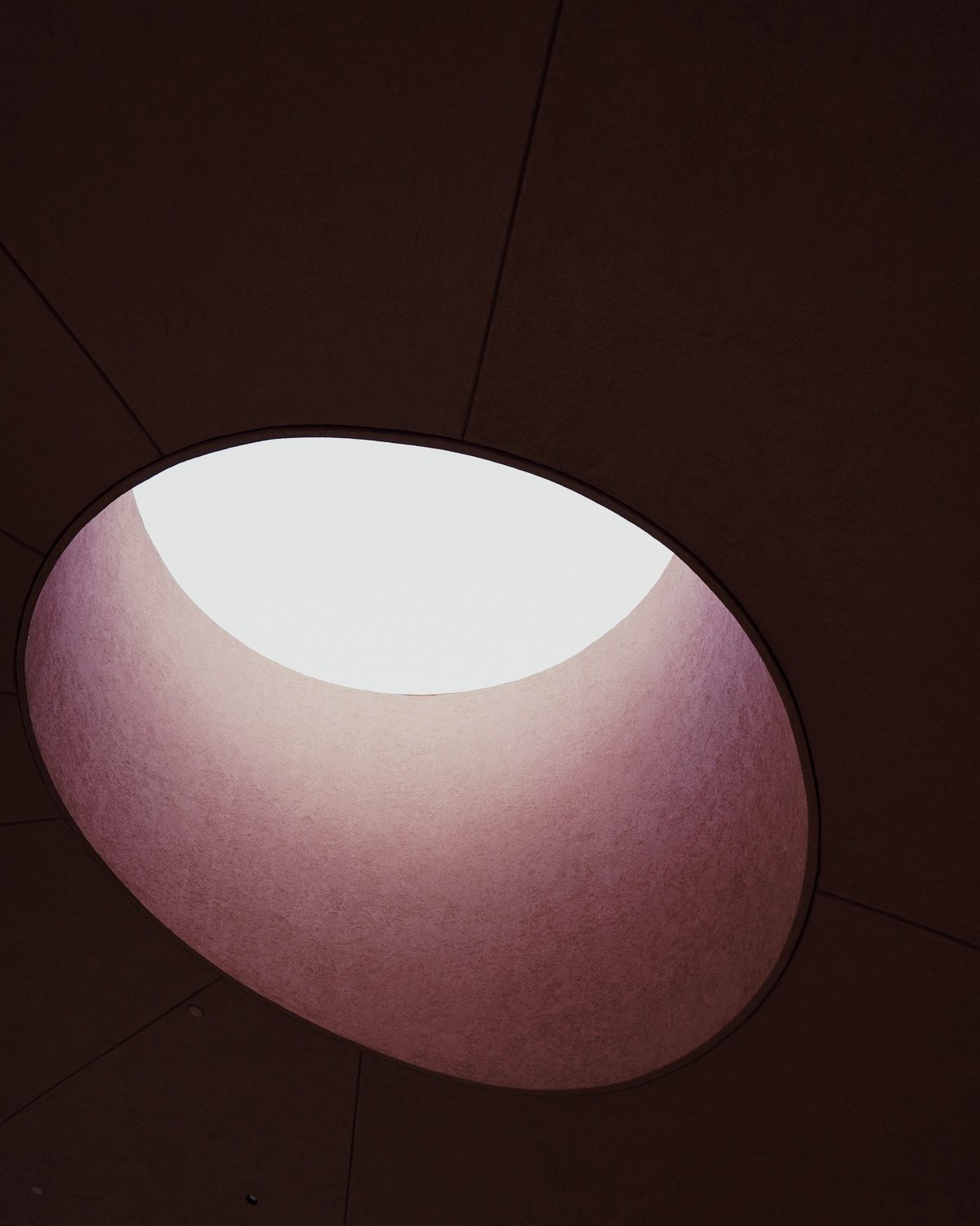 Soft daylight falling through a round skylight onto a dark wall
