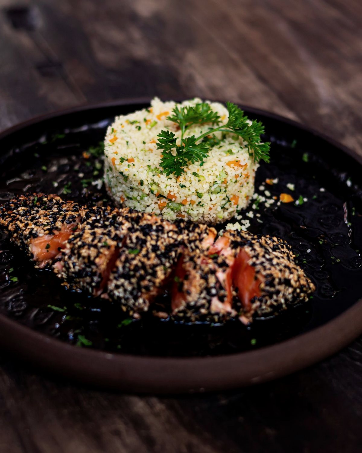 A seasonal plate of fish, grains and herbs on a dark timber table